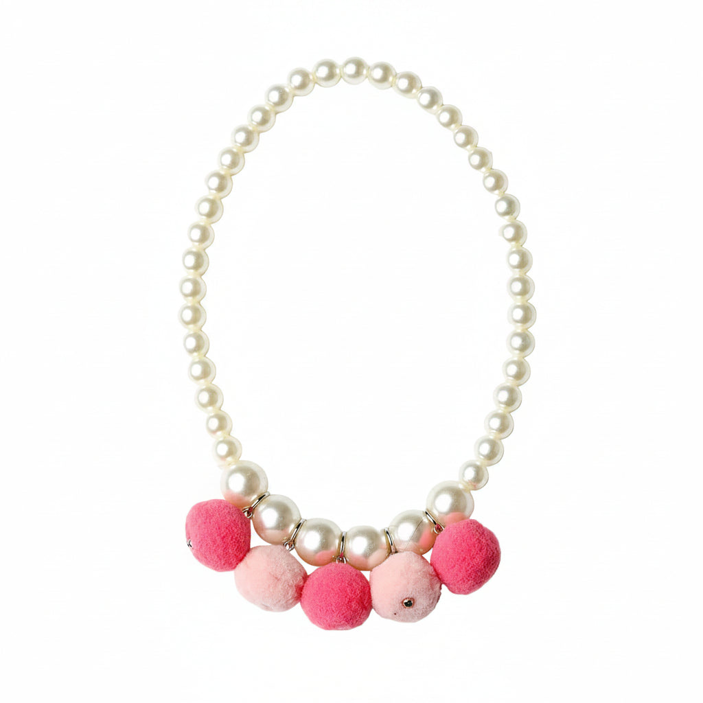 A pearl-bead necklace with a row of fluffy pom-poms in pink and light pink at the bottom, photographed on a clean white background.