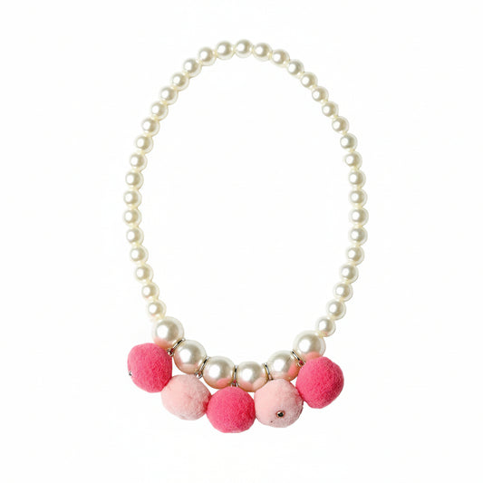 A pearl-bead necklace with a row of fluffy pom-poms in pink and light pink at the bottom, photographed on a clean white background.